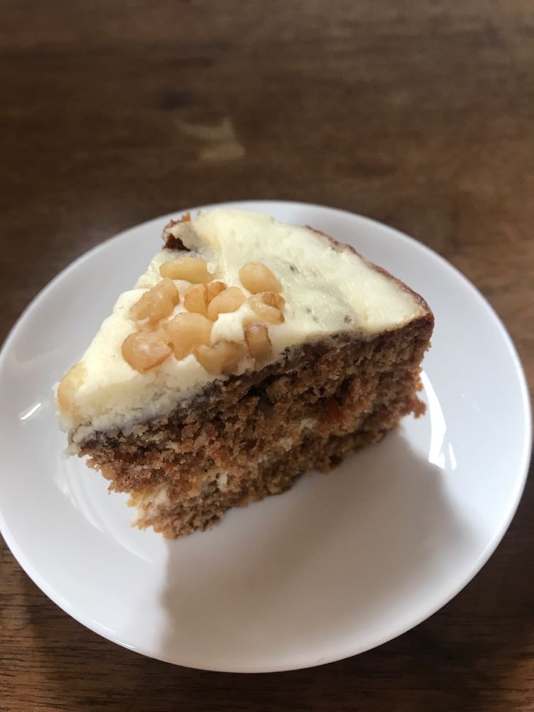 キャロットケーキの一部が白い皿の上に乗っている写真。