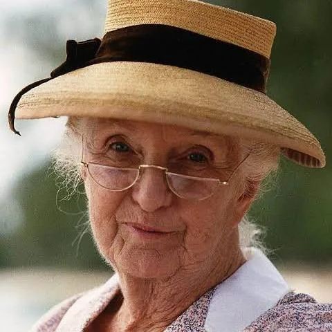 English actor Joan Hickson, wearing a straw hat and half-moon glasses as Miss Marple.