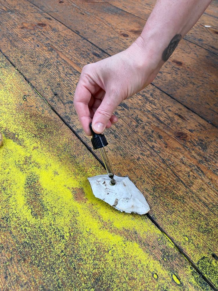 A close up of a hand anointing a stone with oil. 