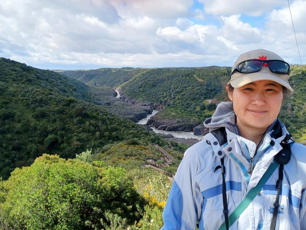 Miya standing with scenary of river and forest behind her