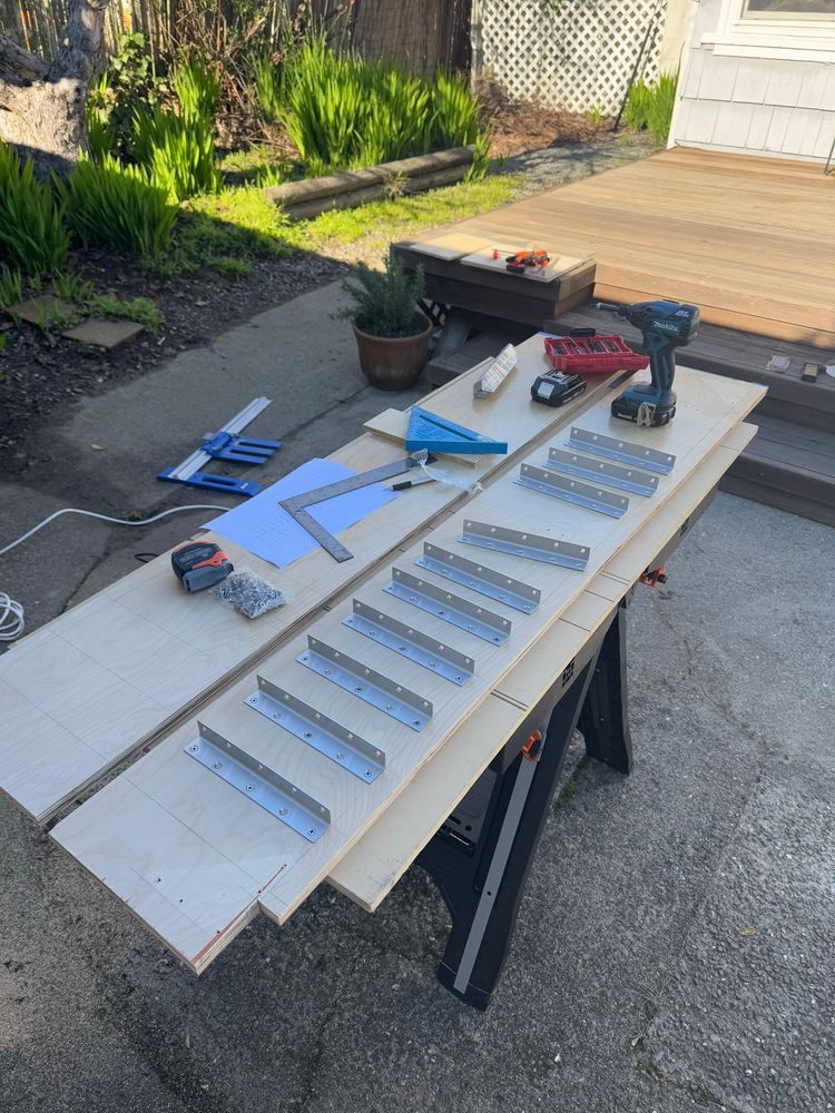 Angle brackets being mounted on the plywood with screws
