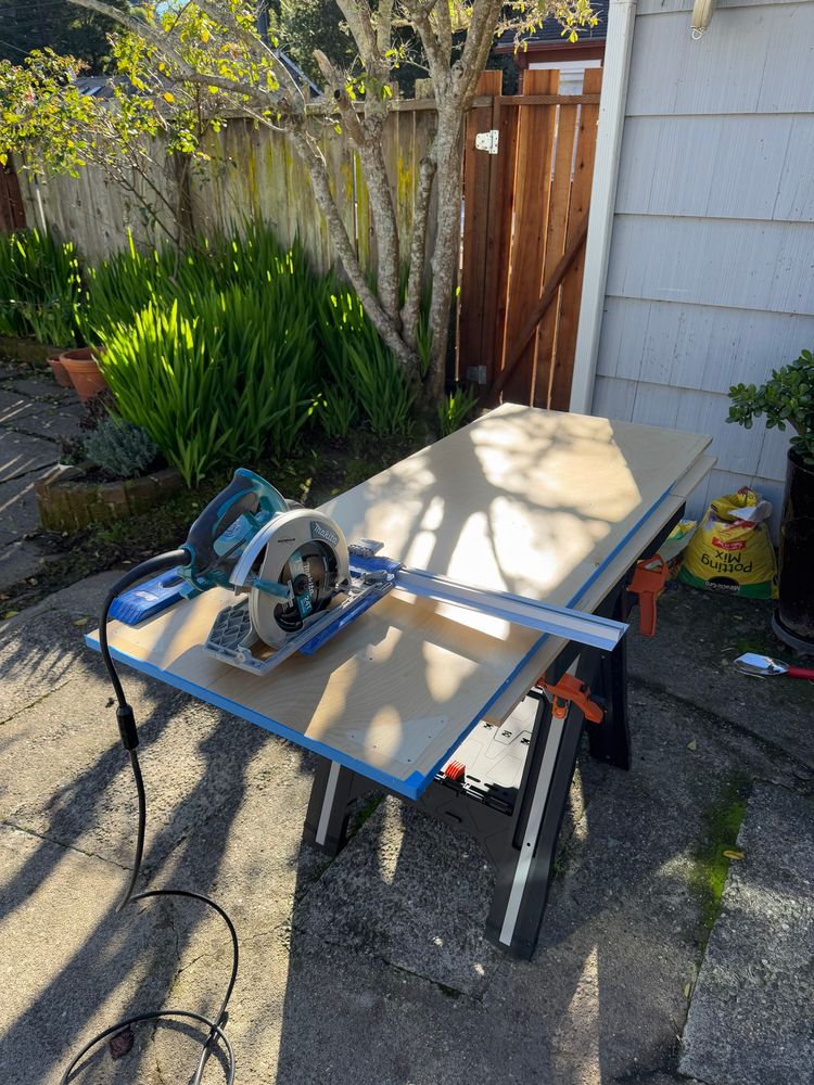 Hand saw sitting on a wood table with plywood on top
