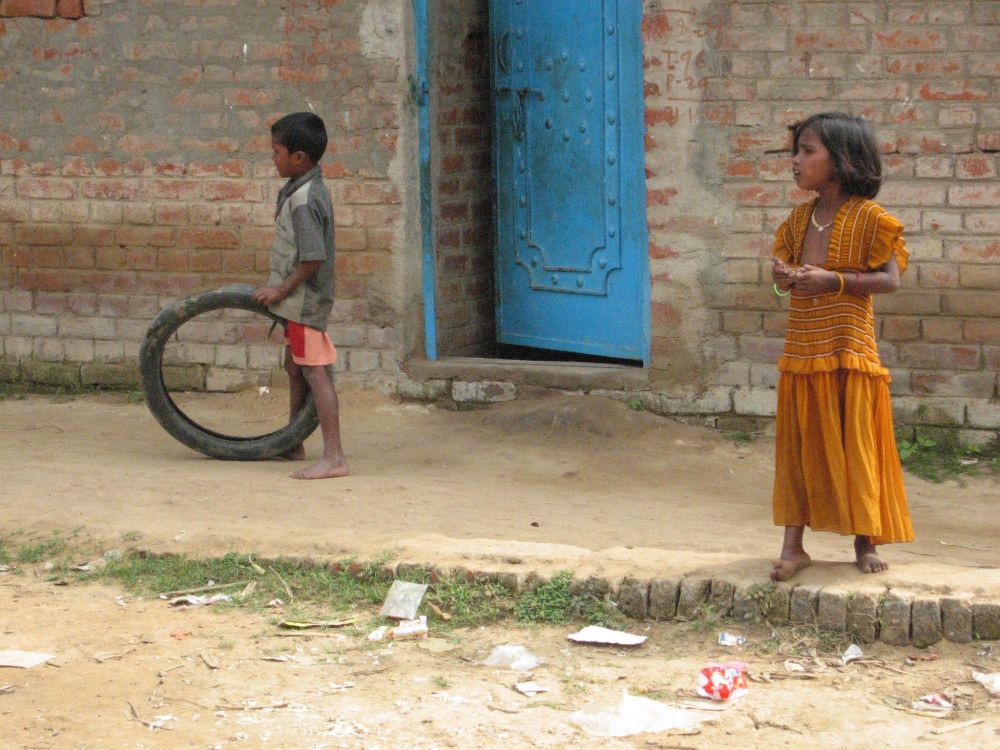 Twee indiaase kinderen armoedig gekleed. Het jongetje heeft een fietsband om mee te spelen. 