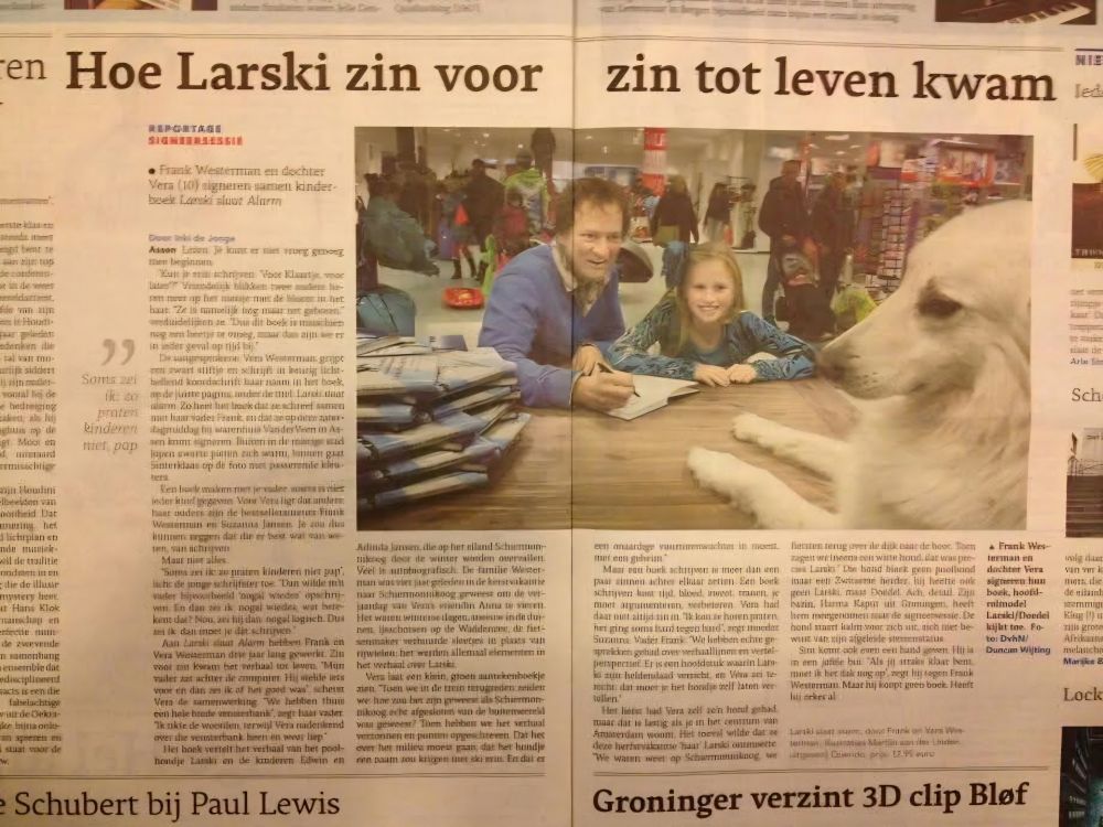 Frank Westerman en zijn dochter signeren een boek voor een hond. 