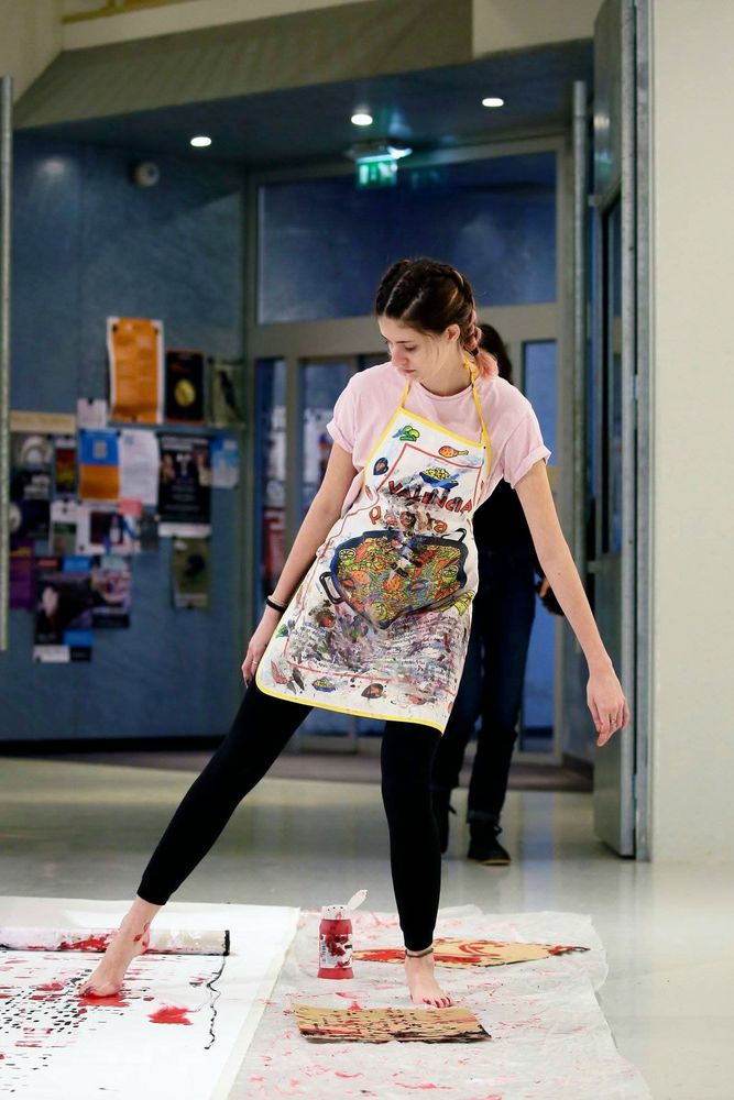 Een vrouw kleurt een stuk stof met haar voeten. 