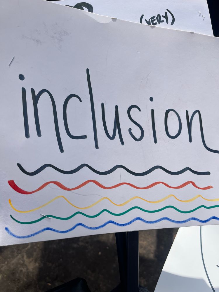 A sign says “inclusion” and underlined in bright colors