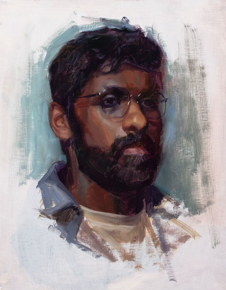 Portrait of a man with dark hair and beard, wearing thin hexagonal eyeglasses and looking serene, maybe a little tired.