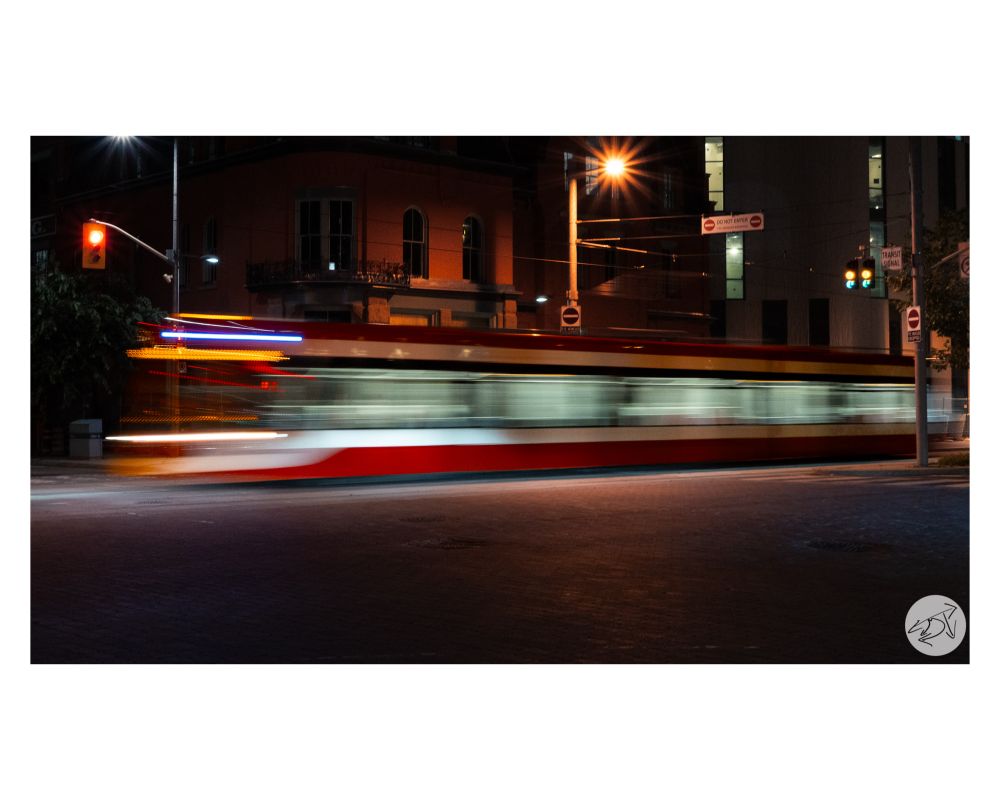 A TTC Streetcar pictured at night moving along the streets of Toronto using a longer shutter speed to distort the shape of the Streetcar