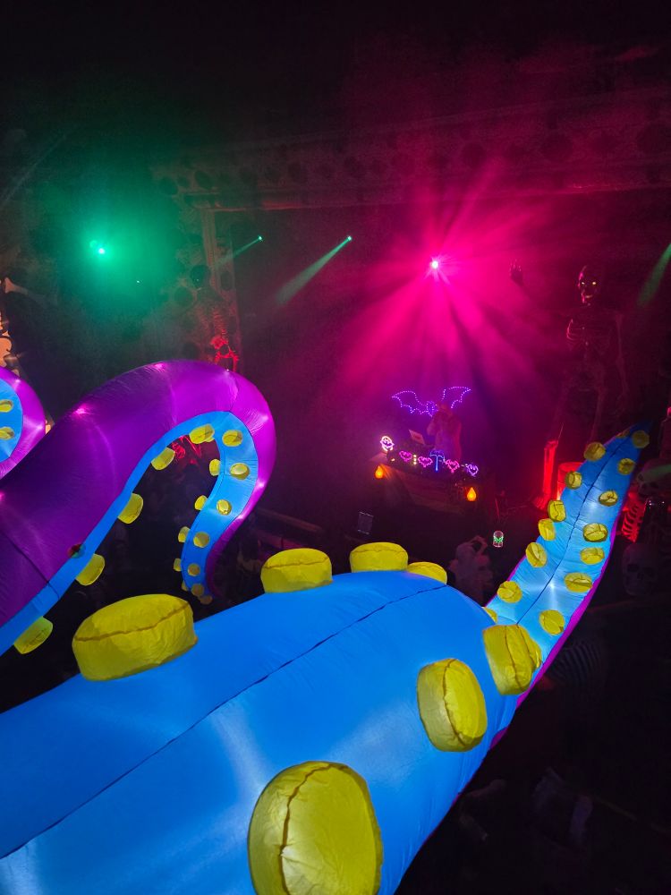 A view of a club stage with wild lighting and inflatable tentacles extending from the balcony.
