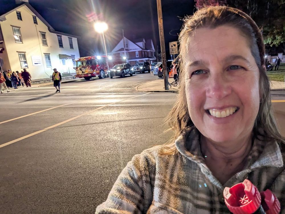 Woman in foreground (Beth Farnham) with a fire service and trick-or-treaters behind.