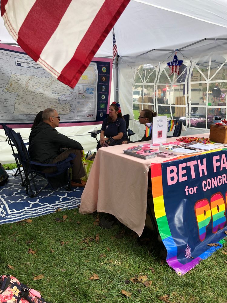 Beth Farnham (woman in blue shirt and flowers in hair) talking with several voters at Pride Franklin County, held at Wilson College, Chambersburg, PA.