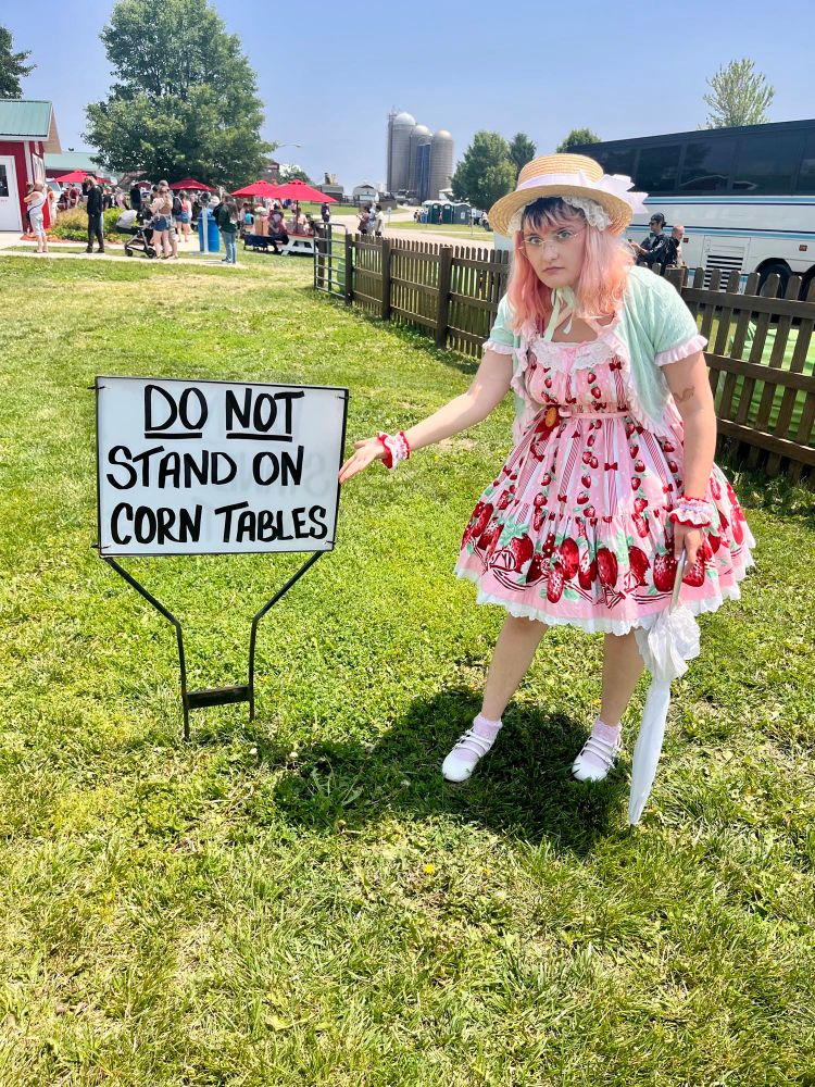 The same person gesturing indignantly, as if to say “How many times do I have to tell you?” at a sign that says “DO NOT STAND ON CORN TABLES” 