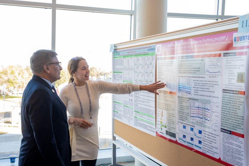 EQUATE graduate student Katherine Johnson (right) shares her research poster with a colleague during a conference.