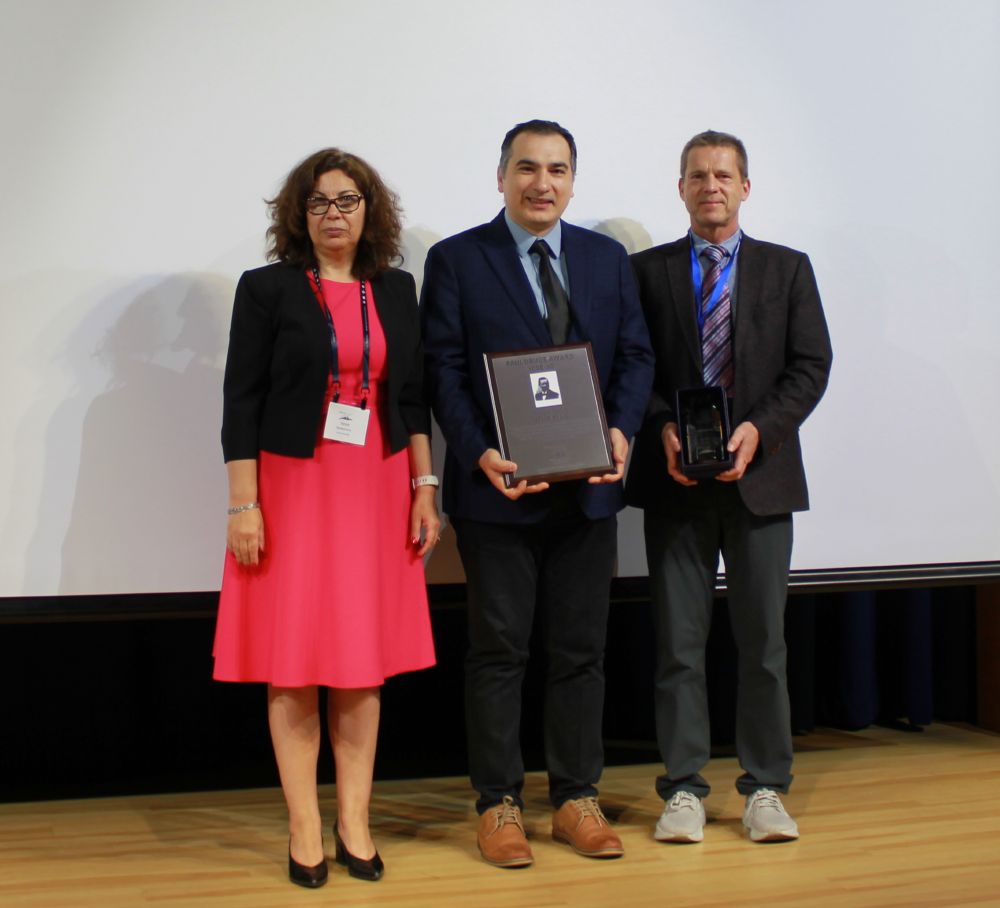 Ufuk Kilic (center) receives the Paul Drude Award at the ICSE-10 event, in June 2025 at Boulder, Colo. He stands with a fellow scientist on his left and on his right.