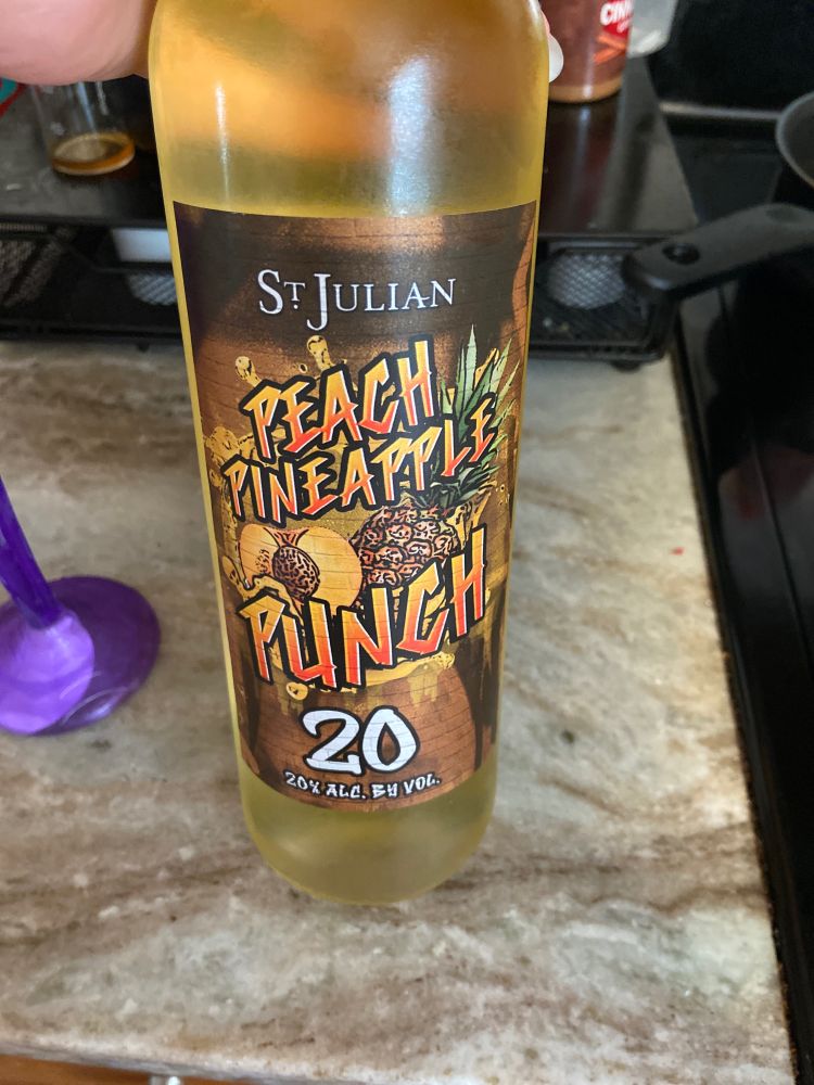 A picture of a bottle of wine, yellow/orange in color in a clear bottle. St. Julian Peach Pineapple Punch. 