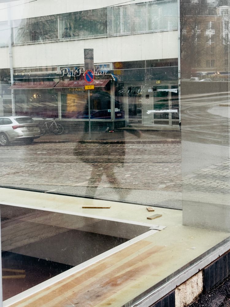 Kulmahuoneiston ikkunaseinät ja ikkunasta heijastuva kävelevä hahmo.