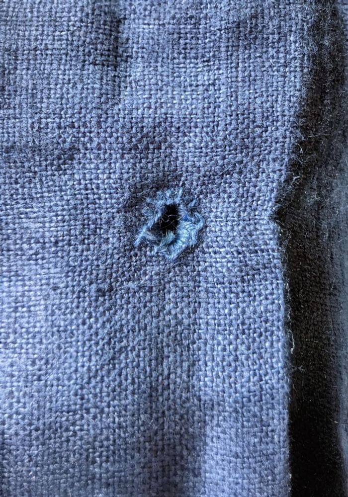 A very wonky eyelet sewn into dark blue linen.