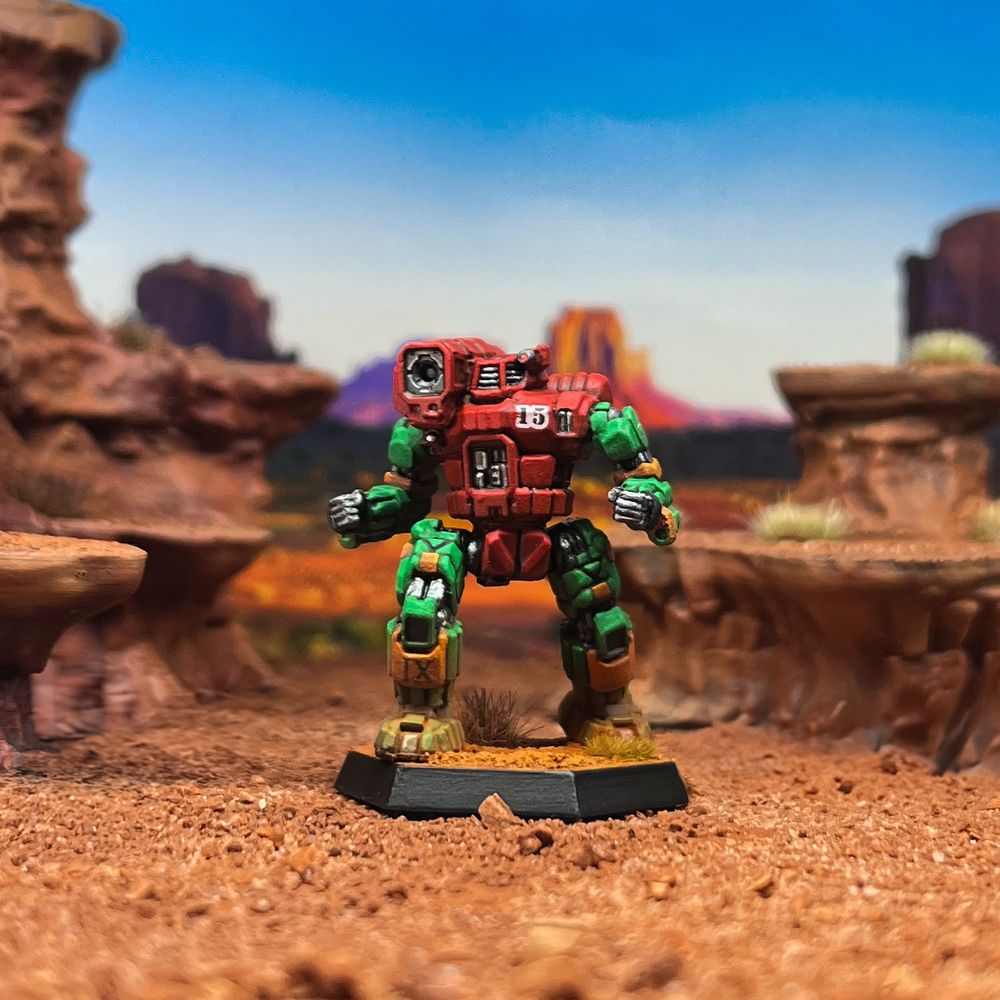 A Hunchback mech painted in the 9th Sian Dragoons scheme of the Capellan Concentration. Red torso, green limbs, orange highlights. Its base is done in a badlands scheme. Photographed from front