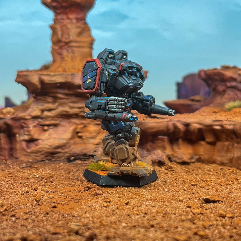 Right shot of an Executioner assault mech. The scheme is in Clan Star Adder Gamma Galaxy colors. Black and dark blue with red highlights. Standing in a badlands photo backdrop. 