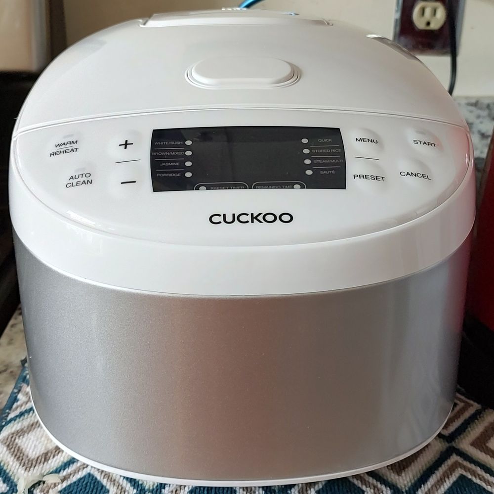 A large white and silver Cuckoo brand rice cooker with multiple cook settings and programmable functions.