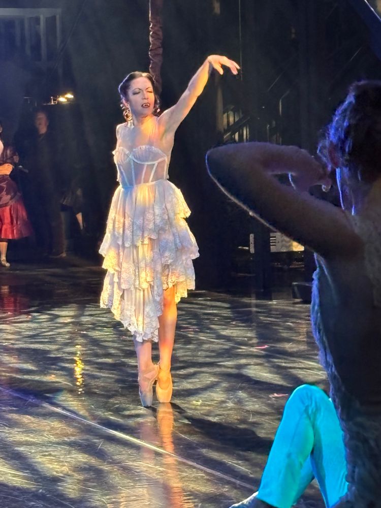 A ballet costume of a white lace bodice and layered lacy white skirt worn by a dancer performing en pointe on stage 