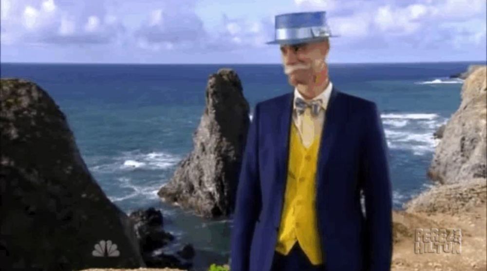 a man in a blue suit and yellow vest is standing on a cliff overlooking the ocean ..