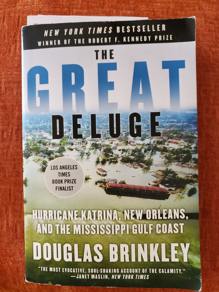 The front cover of a trade paperback called The Great Deluge by Douglas Brinkley. It features an aerial photo of a barge and dozens of houses submerged by flooding.