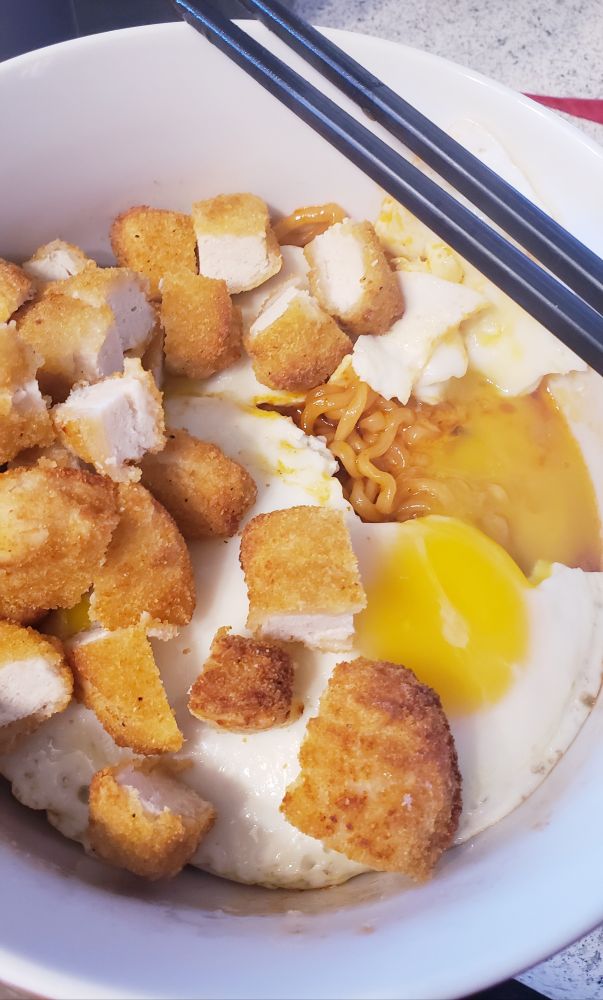 diced chicken and fried eggs with runny yolks over the noodles