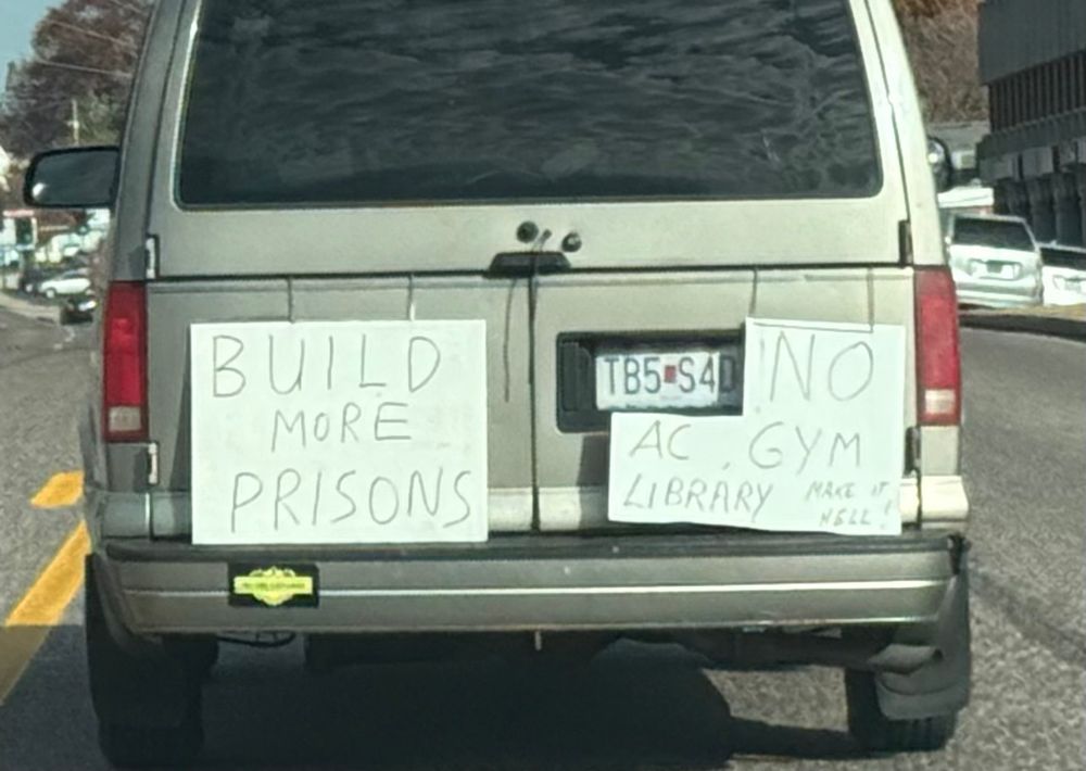 Van with sign on back says “build more prisons. No gym, AC, library. Make it hell