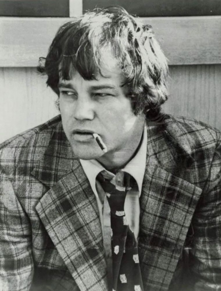 Joe Don Baker on the set of Mitchell in a plaid jacket, huffing a Black and Mild