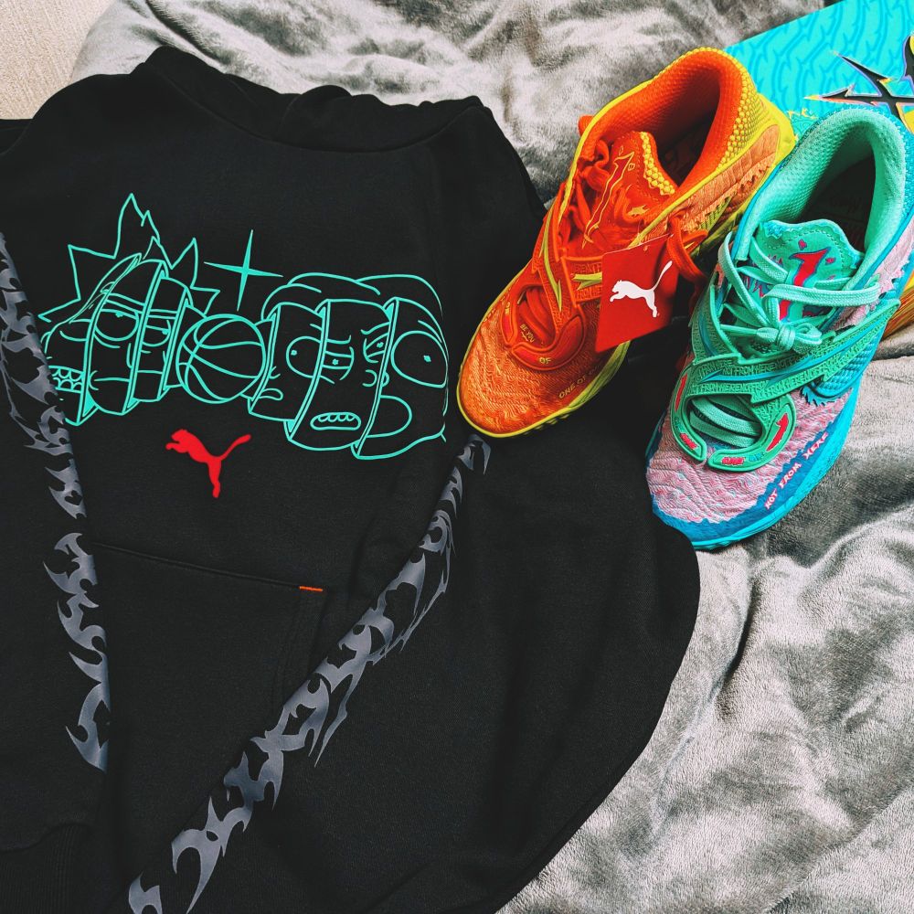 左にはリックとモーティ、バスケットボール、プーマのロゴマークが描かれた黒いパーカー、右にはオレンジと水色のリックアンドモーティコラボシューズが写っている