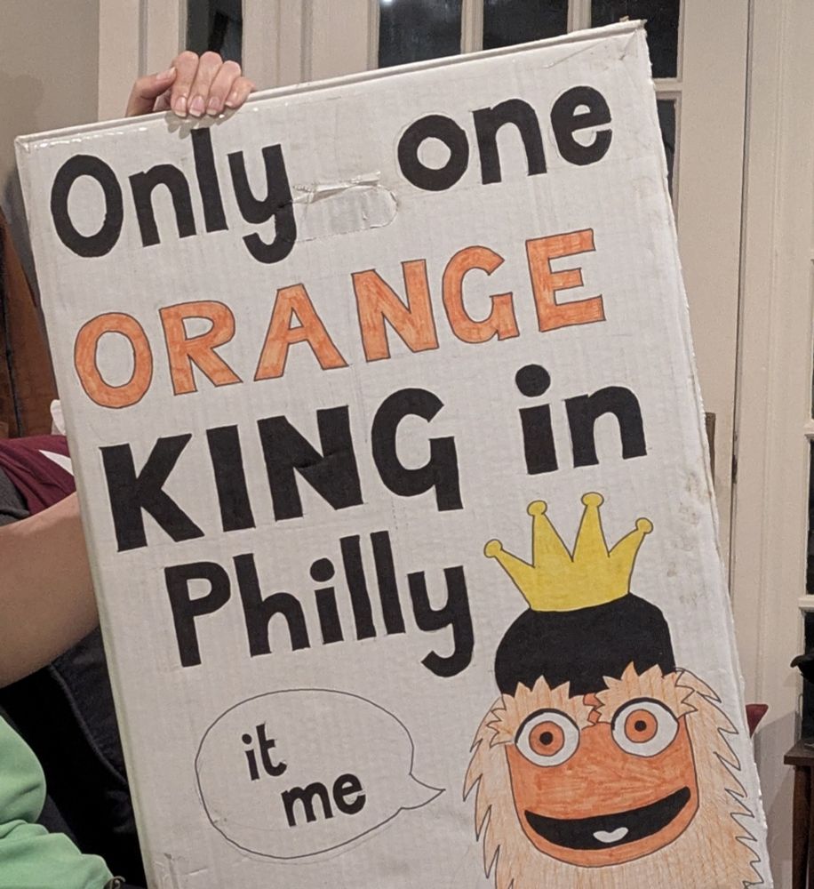 A homemade sign reading "only one orange king in Philly", with a picture of Gritty wearing a crown over his helmet and saying "it me"