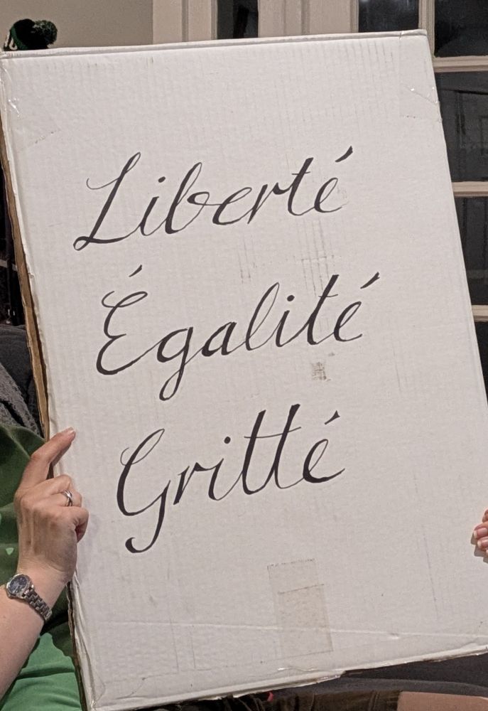 A homemade sign with "Liberté, Égalité, Gritté" written in copperplate script 