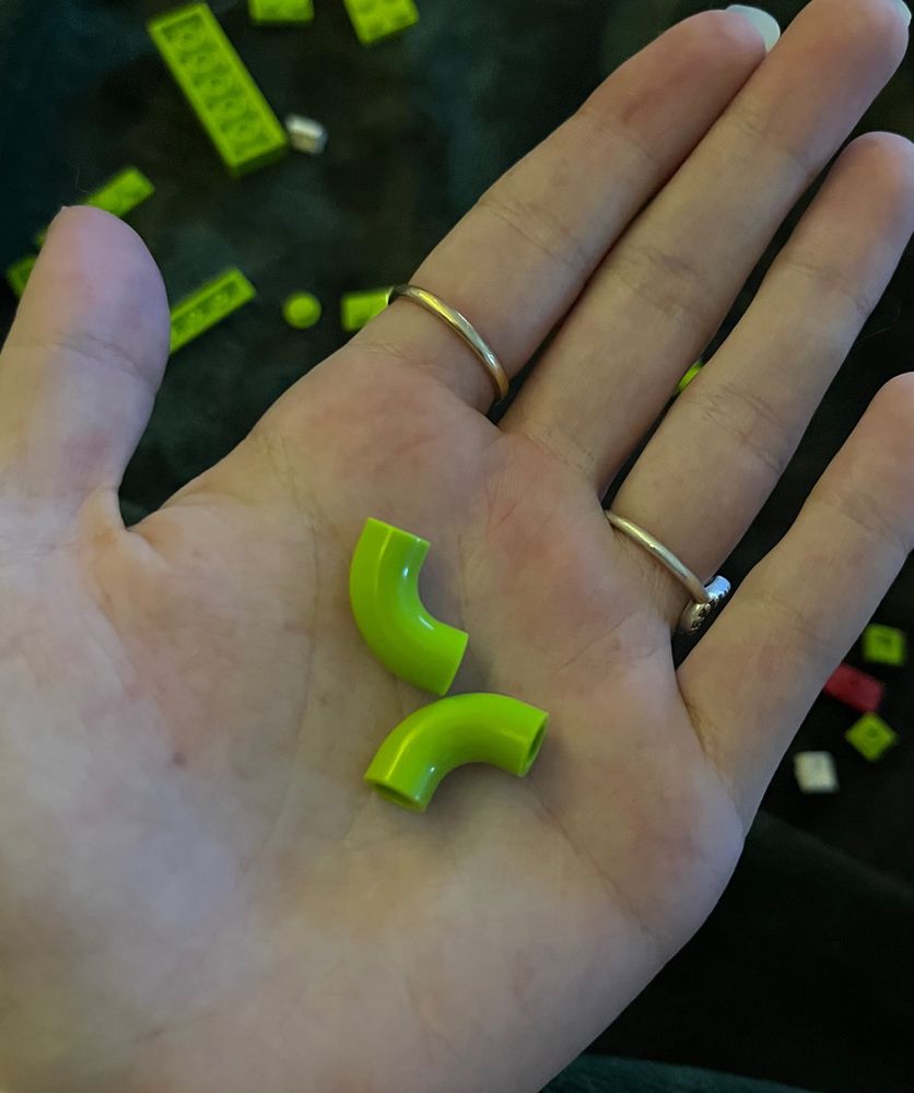 Two Lego pieces that are green and look like elbow noodles 