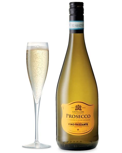 A bottle of Prosecco with a yellow label to the right next to a tall glass full of Prosecco against a white background