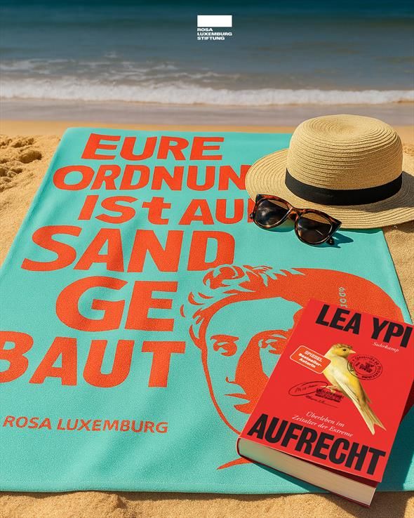 Ein Strandstillleben mit einem Strandhut, einer Sonnenbrille, einem Handtuch mit Rosa-Luxemburg-Zitat ("Eure Ordnung ist auf Sand gebaut.") und dem neuen Buch von Lea Ypi (Aufrecht).