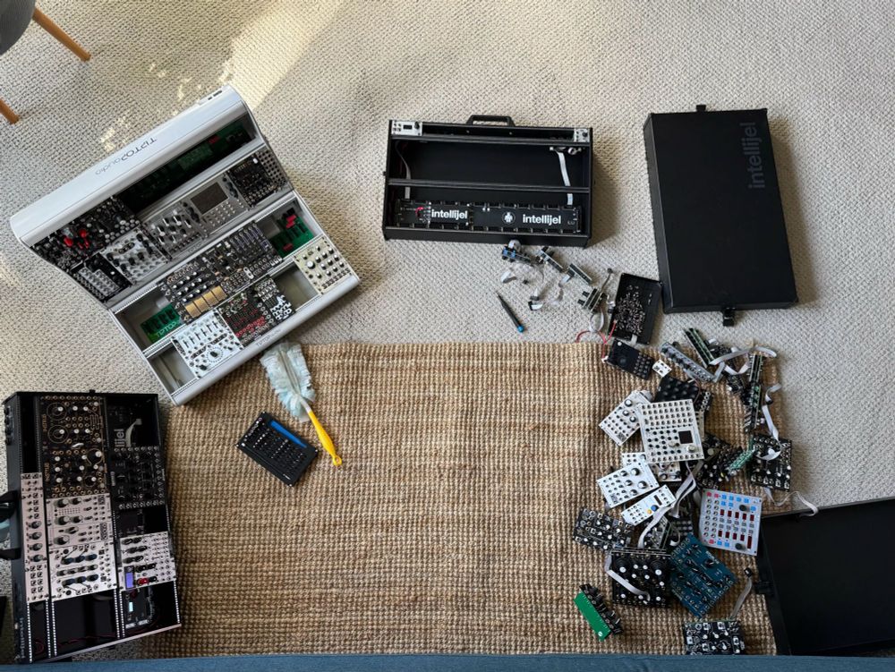 A pile of eurorack modules and cases strewn around the floor