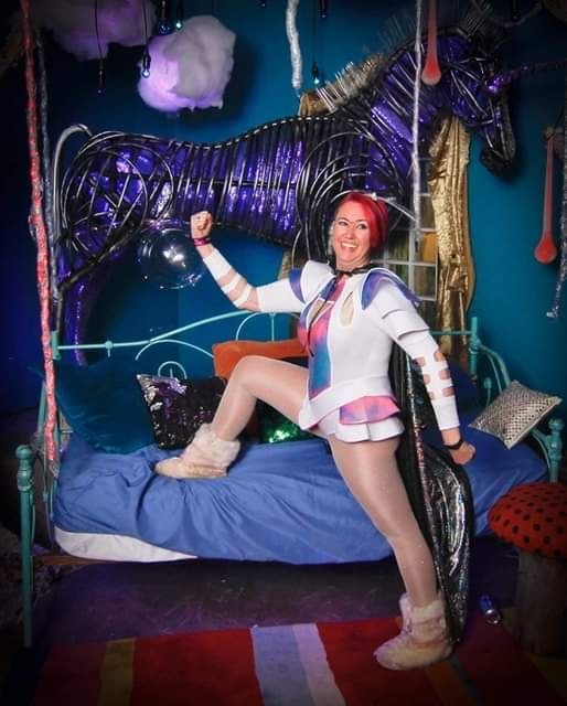 Photo of me wearing a space-y outfitwith fuzzy slipper boots in front of the unicorn my husband made this me.