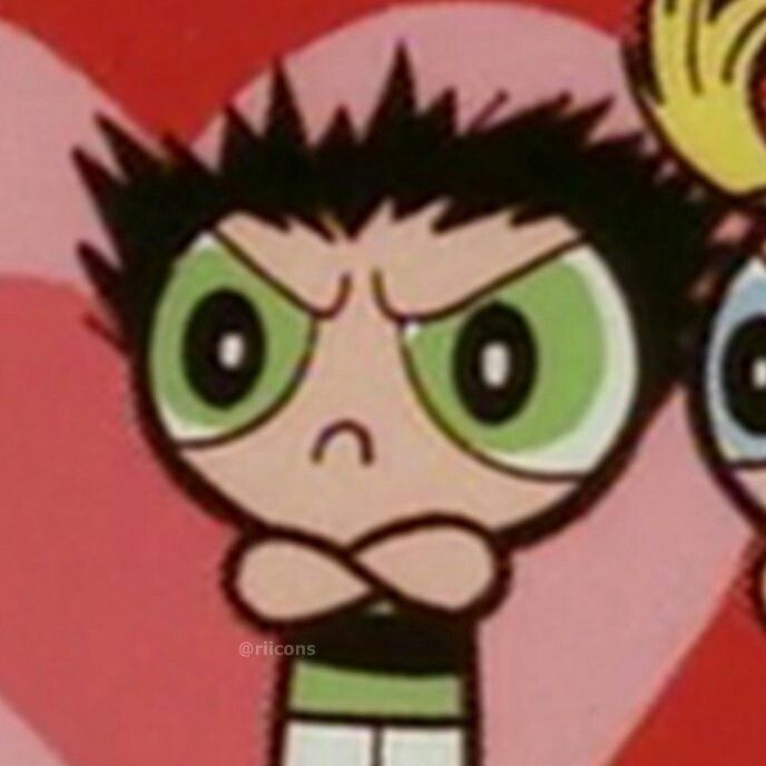 Docinho, da animação "as meninas superpoderosas" é uma menina branca e morena com olhos verdes, está com braços cruzados, cara de muito brava e cabelo pra cima