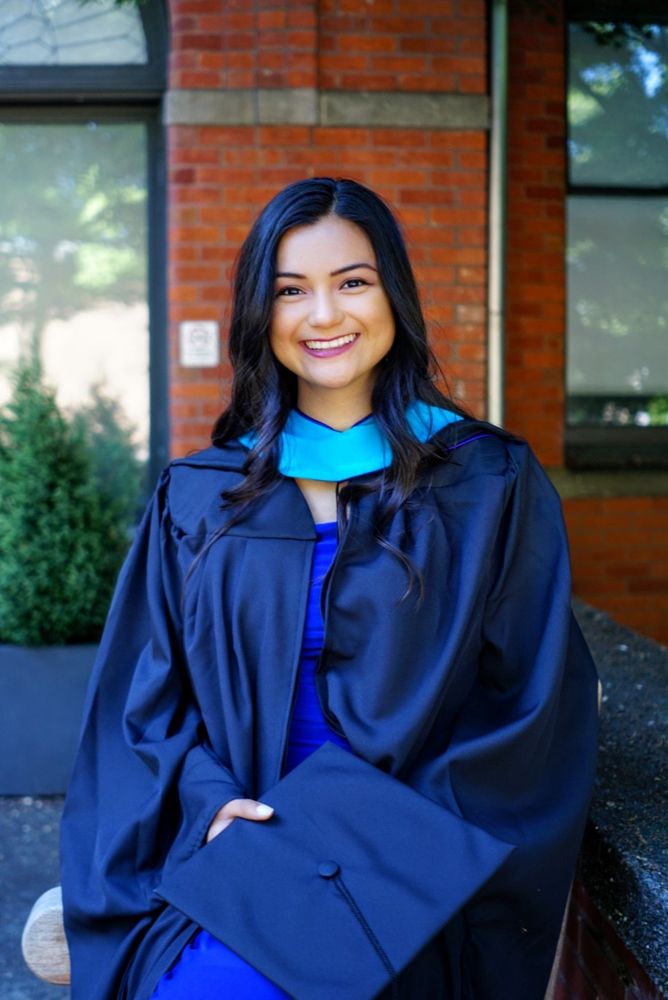 Lucero, myself, outside of my grad school building wearing masters graduation regalia.
