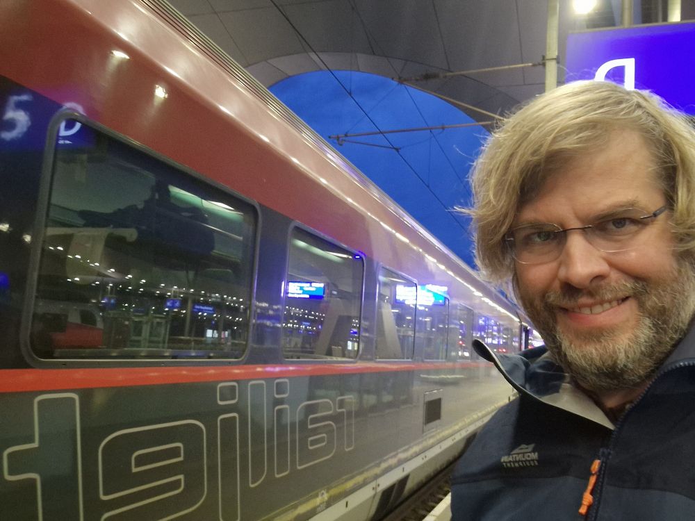 Me, besides a train at Graz main train station. It is getting dark. 