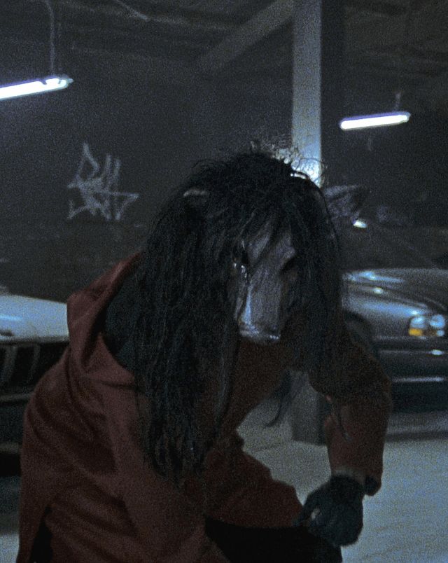 Jigsaw pigmask wearing woman in a car parking deck