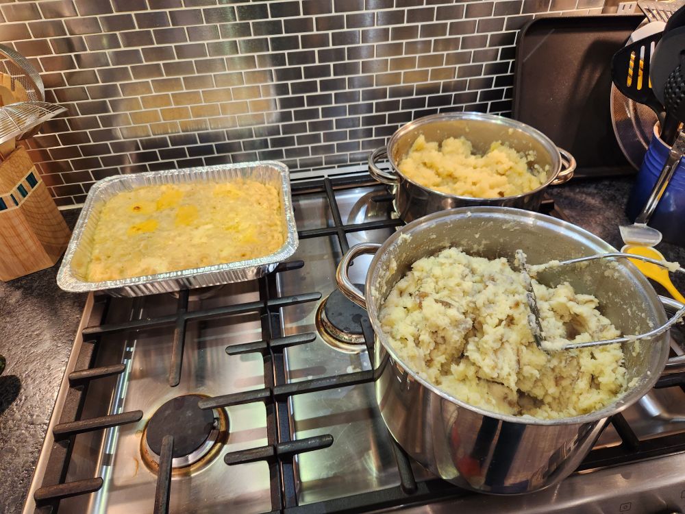 Mac and cheese, garlic dirty mashed potatoes, and dairy free mashed potatoes.  Sitting in pots/containers on a stove. All made from scratch.