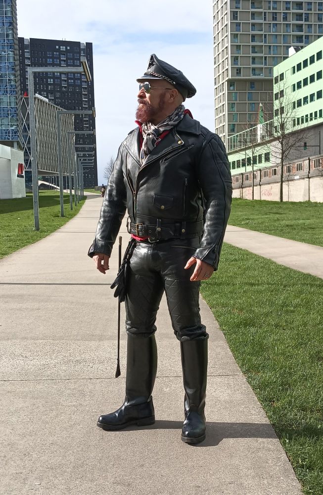 Full leather dressed booted bearded leatherman with muir cap and whip