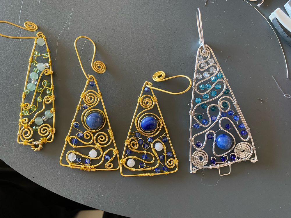 Four Christmas tree decorations in the shape of Christmas trees made of wire and beads