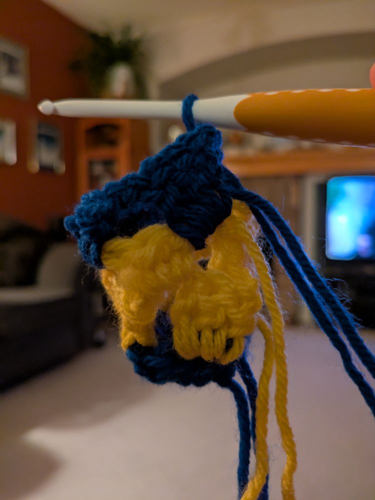 A yellow and blue crochet project that looks a bit weird and sock-like.