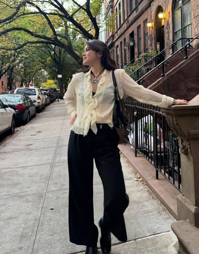 Ti’s kid, the actress in NY, by her Manhattan walk-up. Brunette in a cream top and black pants. 