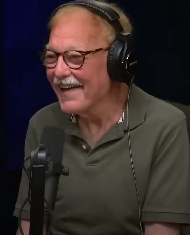 Jim Downey, in headphones and green polo shirt, doing his "Jeff Epstein?" bit on the Conan podcast