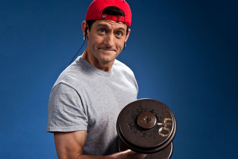 Former Speaker and VP candidate Paul Ryan lifting weights with a backwards red baseball cap and headphones