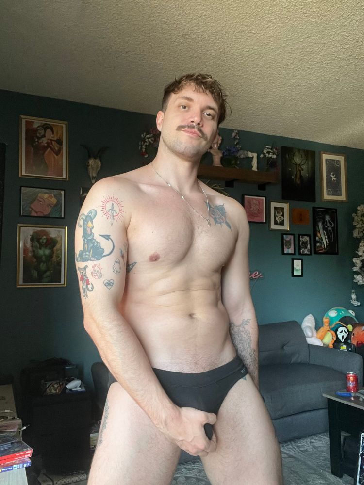 Zach in black briefs grabbing his bulge